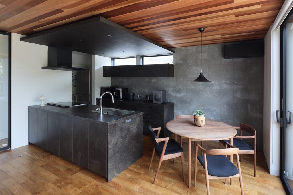 ブラックキッチンと木の天井のダイニング